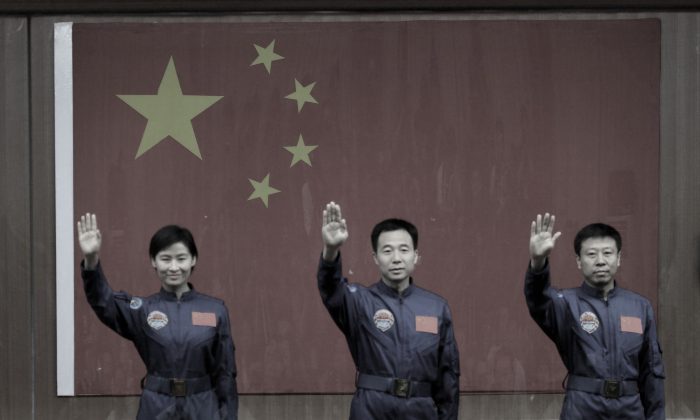 Первая женщина-астронавт Китая Лю Ян (слева) вместе с двумя коллегами-мужчинами на космической базе Цзюцюань, провинция Ганьсу на севере Китая, 15 июня 2012 года. В недавнем отчете, опубликованном Американо-китайской комиссией по обзору экономики и безопасности, анализируются космические программы Китая, и 