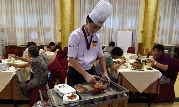 Шеф-повар нарезает утку по-пекински для посетителей в ресторане Quanjude в Пекине 24 июля 2014 года. Китайские местные чиновники часто обедают в ресторанах, надеясь, что государственное финансирование покроет их расходы. (Грег Бейкер / AFP / Getty Images) | Epoch Times Россия