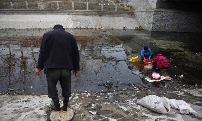 Китайские женщины моют семена 27 ноября 2014 года в заброшенном пекинском канале. (ГРЭГ БЕЙКЕР / AFP / Getty Images) | Epoch Times Россия