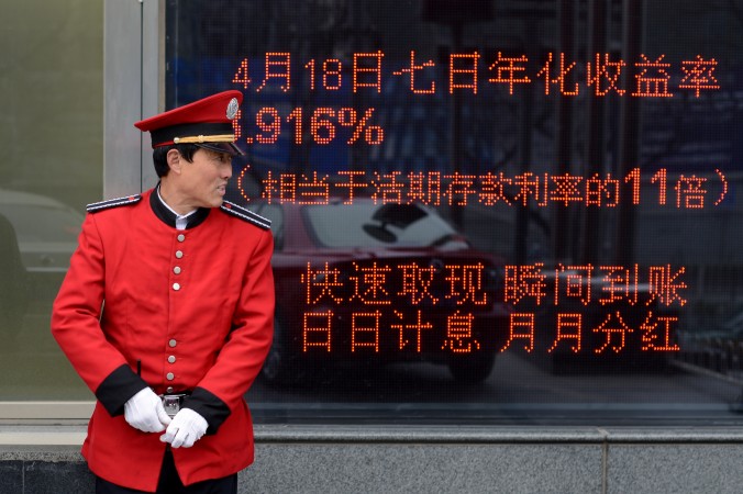 Охранник стоит перед электронным табло у входа в банк в Пекине 23 апреля 2013 года. Фото: WANG ZHAO/AFP/Getty Images | Epoch Times Россия