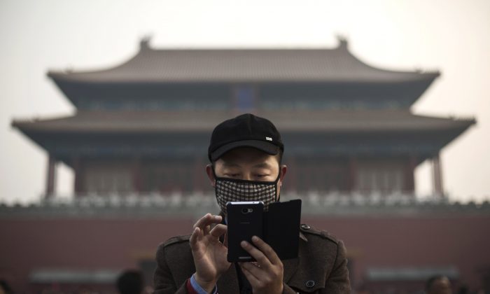 Китаец использует свой смартфон за пределами Запретного города в Пекине 20 ноября 2014 г. (Кевин Фрайер / Getty Images) | Epoch Times Россия