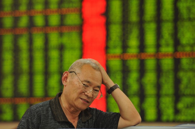 Инвестор проверяет цены акций на фондовом рынке в городе Фуян,  провинция Аньхой на востоке Китая, 26 июня 2015. Фото: STR / AFP / Getty Images | Epoch Times Россия