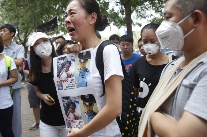 Возле отеля в городе Тяньцзине, где недавно произошло несколько мощных взрывов, женщина (в центе) возмущается нежеланием властей прояснить судьбу пропавшего родственника, который был пожарным, 16 августа, Китай. Фото: STR/AFP/Getty Images | Epoch Times Россия