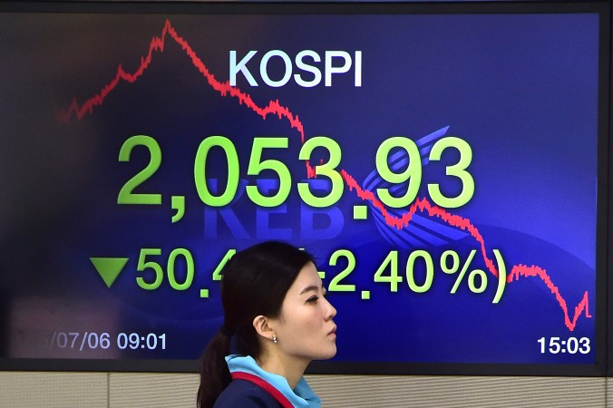 Валютный дилер проходит мимо экрана, на котором показан базовый фондовый индекс Южной Кореи в торговом зале в Exchange Bank Корея в Сеуле на 6 июля 2015 года Фото: Jung Yeon-Je/AFP/Getty Images | Epoch Times Россия