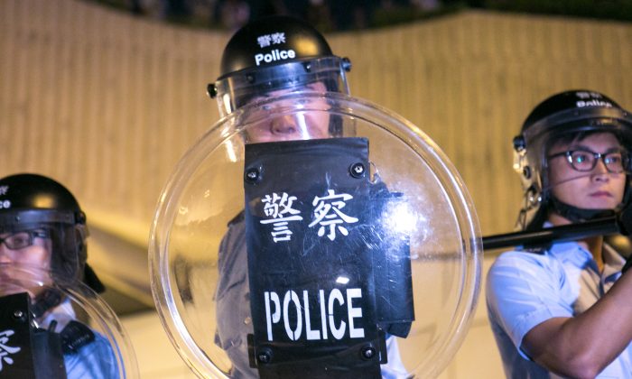 Протестующие, выступающие за демократию, столкнулись с полицией после того, как пытались блокировать Lung Wo Road, одну из главных дорог в Гонконге, в отместку после того, как полиция сняла заграждения и открыла оккупированную дорогу ранее сегодня, 14 октября 2014 г. (Бенджамин). Честин / Великая Эпоха) | Epoch Times Россия