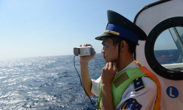 На этом снимке, сделанном 14 мая 2014 года, изображен вьетнамский офицер береговой охраны, фотографирующий китайское судно береговой охраны возле китайской буровой установки в спорных водах Южно-Китайского моря. (Хоанг Динь Нам / AFP / Getty Images) | Epoch Times Россия
