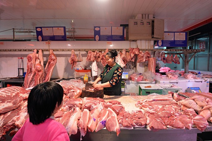 Мяcник разделывает тушу свиньи для продажи в Пекине, 15 февраля 2015 года. Фото: STR/AFP/Getty Images | Epoch Times Россия