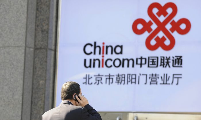 Офисный работник разговаривает по мобильному телефону перед логотипом China Unicom, калифорнийского партнера Apple в Китае, в Пекине, 5 января 2012 г. (Лю Цзинь / AFP / Getty Images) | Epoch Times Россия