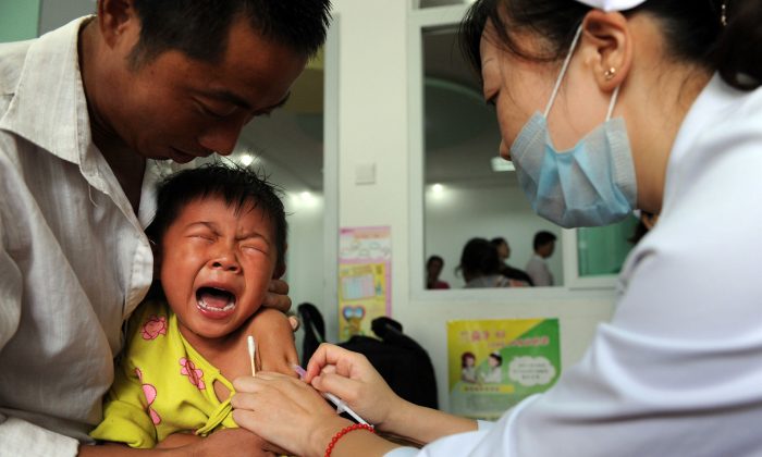Ребенку делают прививку от кори в провинции Аньхой на востоке Китая 11 сентября 2010 года. Полиция остановила незаконный бизнес по продаже зараженных вакцин в провинции Шаньдун. (STR / AFP / Getty Images) | Epoch Times Россия