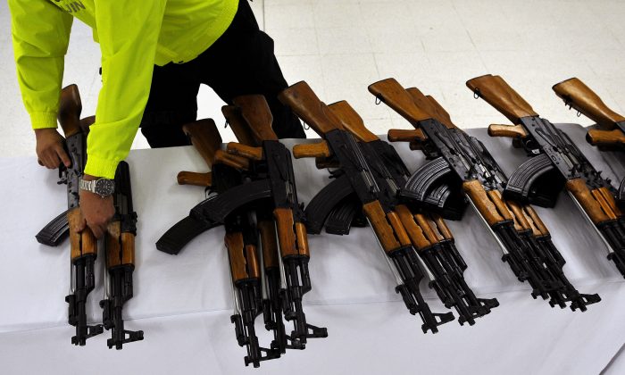 Сотрудник полиции Колумбии организует изъятие автоматов в Кали, департамент Валье-дель-Каука, Колумбия, 29 июля 2011 года. Колумбийская полиция изъяла 47 7,62-мм автоматов Norinco китайского производства (копии AK-47) и 214 магазинов. (Луис Робайо / AFP / Getty Images) | Epoch Times Россия