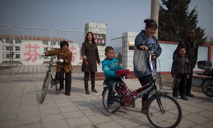Родители и дети покидают школу в Чэндэ, провинция Хэбэй, 21 марта 2013 года. Женщины среднего возраста снова беременеют после того, как Китай ослабил политику одного ребенка. (Эд Джонс / AFP / Getty Images) | Epoch Times Россия