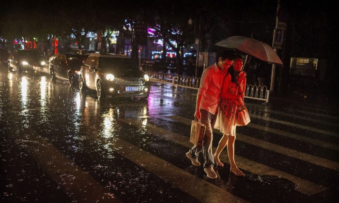 Китайская пара гуляет вместе под зонтиком дождливым вечером 4 сентября 2014 года в Пекине, Китай. (Фото Кевина Фрайера / Getty Images) | Epoch Times Россия