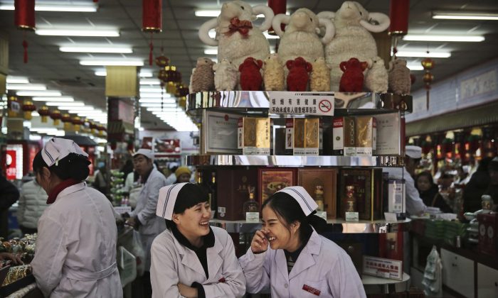 Китайские клерки болтают, ожидая покупателей на рынке в Пекине 19 января 2016 г. (Кевин Фрайер / Getty Images) | Epoch Times Россия