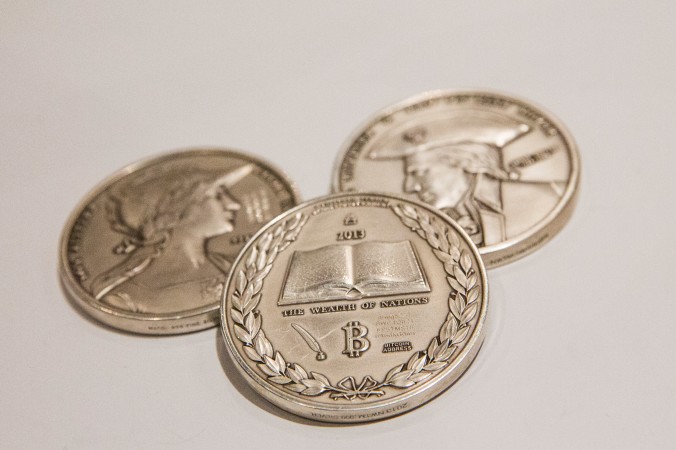 Серебряные монеты с логотипом Bitcoin представлены на конференции по Bitcoin в Javits Center 7 апреля 2014 года в Нью-Йорке. Фото: Andrew Burton/Getty Images | Epoch Times Россия