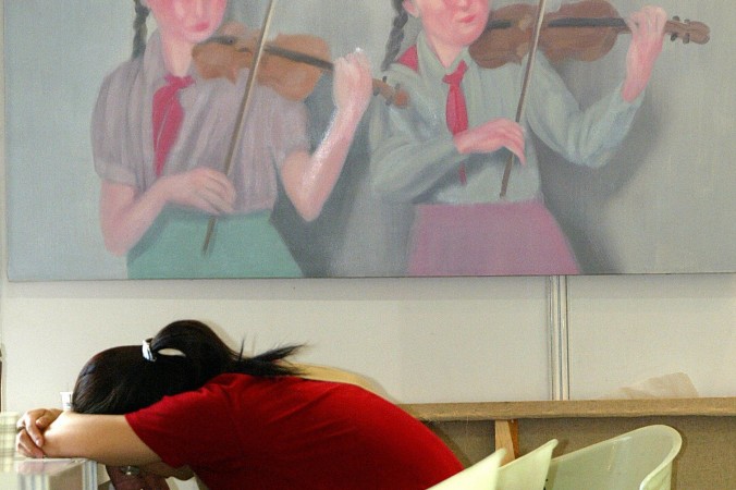 Женщина дремлет перед изображением двух пионерок, играющих на скрипках, Шанхай, 3 июня 2004 года. Фото: Liu Jin/AFP/Getty Images | Epoch Times Россия