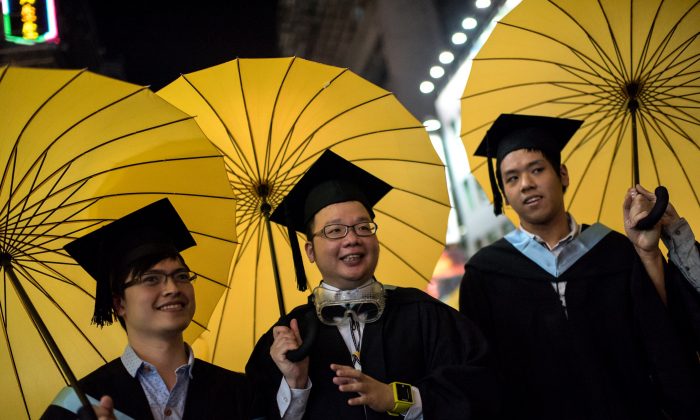Студенты колледжа в выпускной одежде несут желтые зонтики, символы продемократического движения в Гонконге, когда они позируют для фотографий в районе Монгкок Гонконга 19 октября 2014 года. Десятки студентов держали зонтики во время выпускной церемонии в Лингнане Университет в Гонконге призвал главу школы справедливо провести переговоры между исполнительным директором и студентами, выступающими за демократию. (Алекс Огл / AFP / Getty Images) | Epoch Times Россия