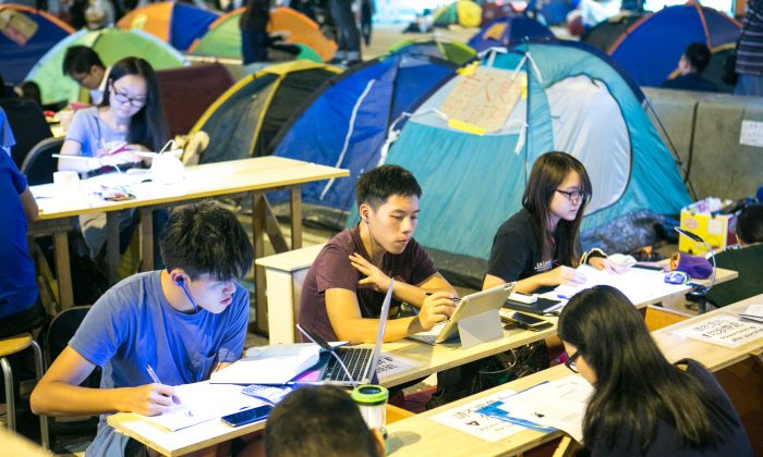 Студенты работают в так называемом «Учебном уголке», который был создан несколькими активистами, чтобы студенты могли делать домашнее задание и учиться, одновременно протестуя в центральном районе Гонконга 14 октября 2014 года. В кабинете есть генератор, который обеспечивает электричество, а также работает Wi-Fi для студентов. (Бенджамин Честин / Великая Эпоха) | Epoch Times Россия