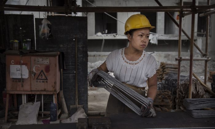 Китайская женщина-строитель работает на строительной площадке нового жилого комплекса в Пекине 29 августа 2014 г. (Кевин Фрайер / Getty Images) | Epoch Times Россия