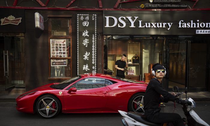 Китаец пользуется телефоном рядом со своим Ferrari в престижном торговом районе Пекина 29 мая 2015 г. (Кевин Фрайер / Getty Images) | Epoch Times Россия