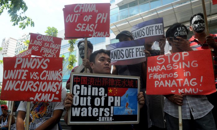 Протестующие проводят митинг перед китайским консульством в финансовом районе Манилы 7 июля, осуждая претензии китайского режима на Южно-Китайское море. Китайские власти могут вскоре начать вторую фазу строительства острова в спорных водах. (Джей Директо / AFP / Getty Images) | Epoch Times Россия