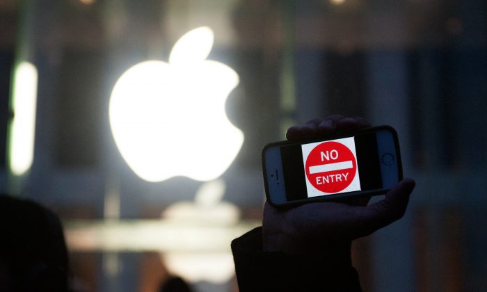 Протестующий держит iPhone с надписью «Вход запрещен» возле магазина Apple на 5-й авеню в Нью-Йорке 23 февраля. Хотя Apple утверждает, что поддерживает конфиденциальность пользователей в США, она тесно сотрудничает с властями Китая. . (Брайан Томас / Getty Images) | Epoch Times Россия