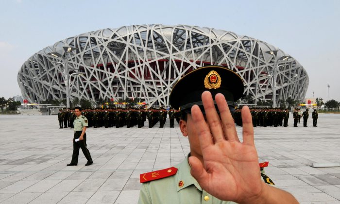 Китайский военизированный полицейский пытается заблокировать фотоснимки репетиции военного парада у Олимпийского стадиона в Пекине 21 июля. (Mark Ralston / AFP / Getty Images) | Epoch Times Россия