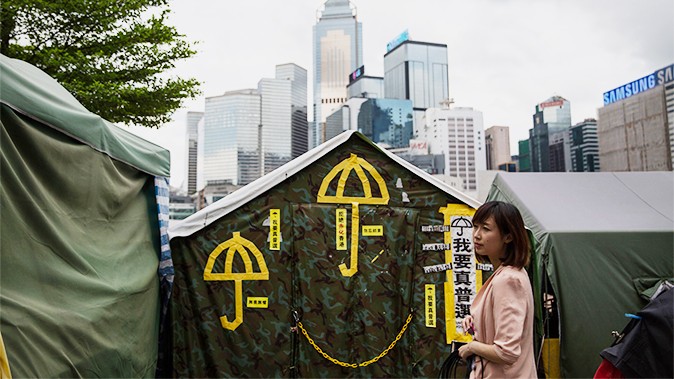 Женщина стоит перед желтыми зонтиками, символом продемократического движения, застрявшими в палатке возле штаб-квартиры правительства в Гонконге 13 июня 2015 г. (Dale de la Rey / AFP / Getty Images) | Epoch Times Россия