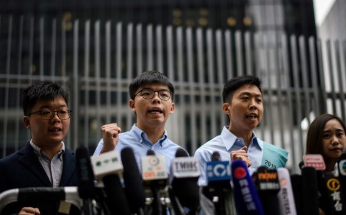 Активист движения за демократию Джошуа Вонг (2-й слева) и Кельвин Лэм (2-й справа) выкрикивают лозунги на встрече со СМИ у Законодательного совета в Гонконге, 29 октября 2019 года. Фото: ANTHONY WALLACE/AFP via Getty Images | Epoch Times Россия