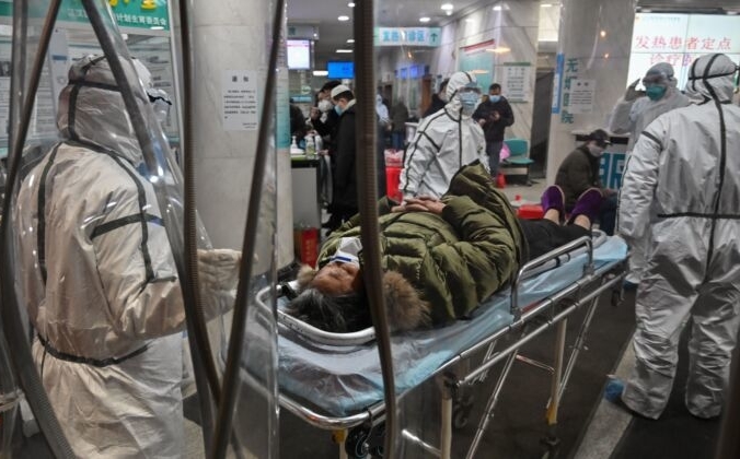Медицинский персонал в защитной одежде прибыл с пациентом в больницу Красного Креста в Ухане, Китай, 25 января 2020 года. HECTOR RETAMAL/AFP via Getty Images | Epoch Times Россия