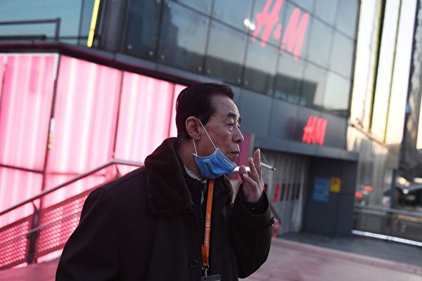 Мужчина опускает маску, чтобы выкурить сигарету, Пекин, 17 февраля 2020 года. GREG BAKER/AFP via Getty Images | Epoch Times Россия