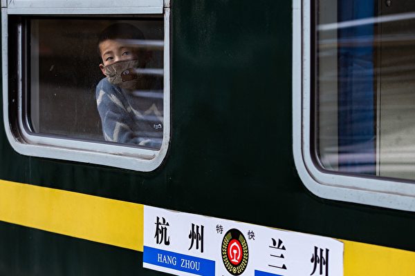Мальчик в защитной маске сидит в поезде на железнодорожной станции Нанкин провинции Цзянсу,18 февраля 2020 года.  STR/AFP via Getty Images | Epoch Times Россия