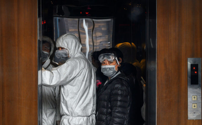 Коронавирус COVID-19. Китайские рабочие в защитных костюмах стоят в лифте в торговом центре 9 февраля 2020 года в Пекине, Китай. Kevin Frayer/ Getty Images | Epoch Times Россия