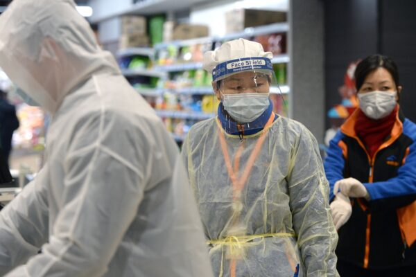 Человек в защитной маске и костюме в супермаркете Уханя. STR/AFP via Getty Images | Epoch Times Россия