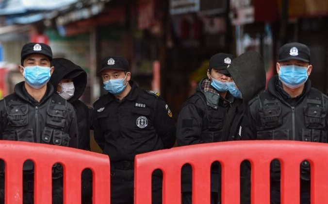 Полицейские и охранники стоят возле оптового рынка морепродуктов Хуанань, где 24 января 2020 года в Ухане был обнаружен коронавирус.  HECTOR RETAMAL/AFP via Getty Images | Epoch Times Россия