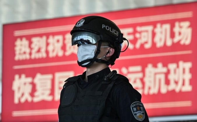 Полицейский в маске стоит на страже в аэропорту Тяньхэ после его открытия в Ухане, Китай, 8 апреля 2020 года. HECTOR RETAMAL/AFP via Getty Images | Epoch Times Россия