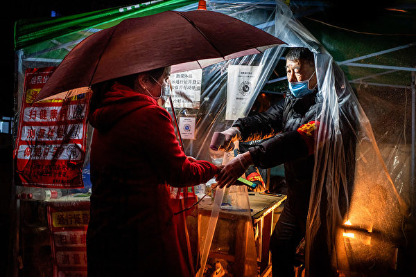 Сотрудник проверяет температуру жительницы перед входом в жилое сообщество города Муданьцзян провинции Хэйлунцзян, 20 апреля 2020 года. STR/AFP via Getty Images | Epoch Times Россия