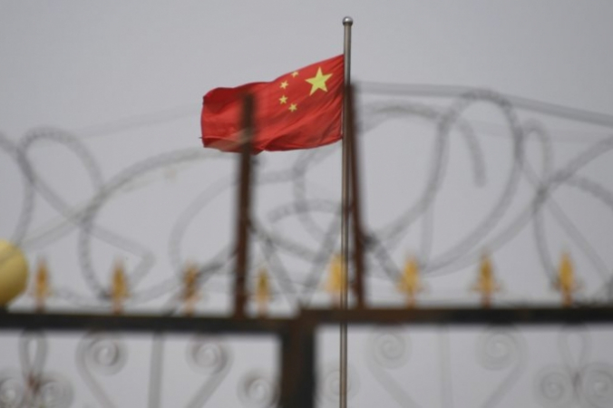 Китайский флаг за колючей проволокой на жилом комплексе в уезде Янгисаре, к югу от Кашгара, Синьцзян-Уйгурский автономный район, 4 июня 2019 года. Greg Baker/AFP via Getty Images | Epoch Times Россия