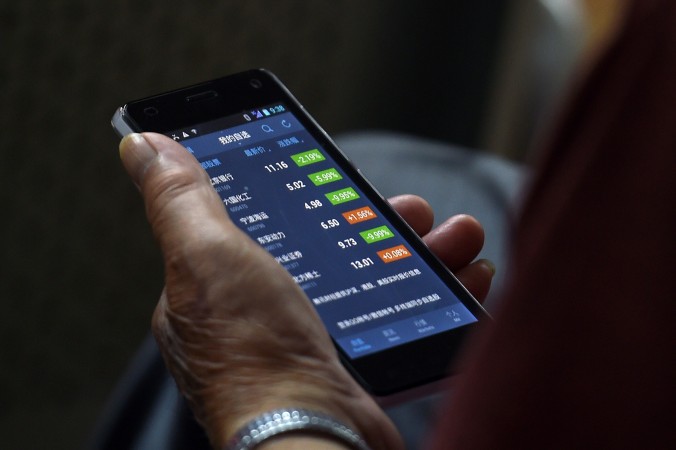 Инвестор проверяет цены акций на своём смартфоне, Пекин, 9 июля 2015 г. Фото: GREG BAKER/AFP/Getty Images | Epoch Times Россия