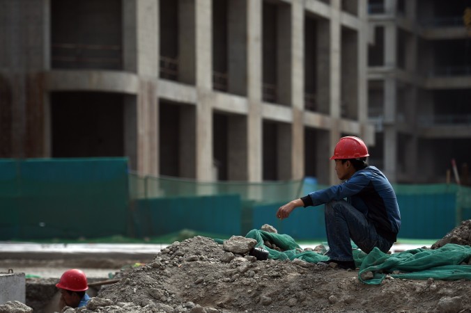 Строитель отдыхает у здания нового финансового центра в районе Юцзяпу в Тяньцзине, 14 мая 2015 г. Фото: Greg Baker/AFP/Getty Images | Epoch Times Россия