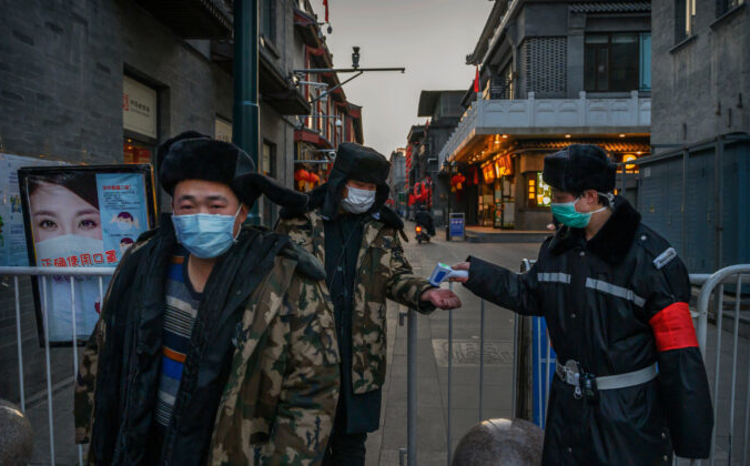 Охранник проверяет температуру у людей на временном входе в коммерческую зону в Пекине, 11 марта 2020 года. Kevin Frayer/Getty Images | Epoch Times Россия