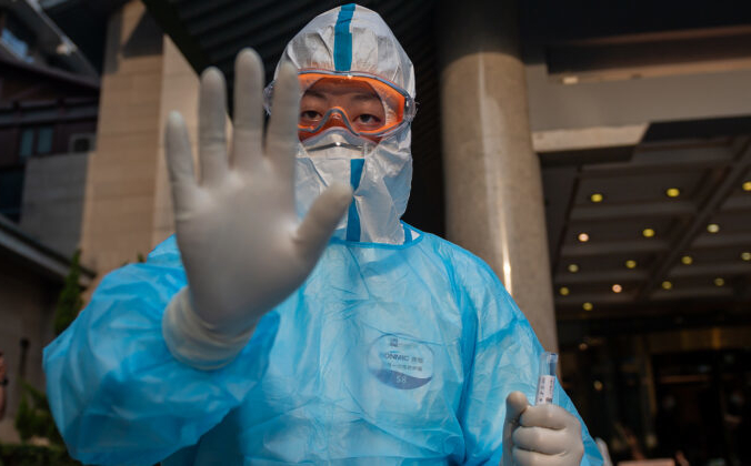Медицинский работник в полном защитном снаряжении готовится взять у репортёра образцы для тестирования на COVID-19  в отеле «Дяоюйтай» в Пекине 28 мая 2020 года. Nicolas Asfouri/AFP via Getty Images | Epoch Times Россия