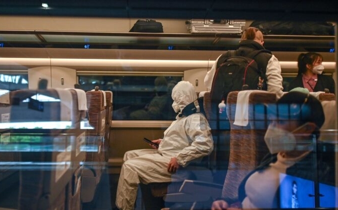 Мужчина в защитном костюме садится в поезд, направляющийся в Шанхай, на железнодорожном вокзале «Ухань» в городе Ухане, центральной китайской провинции Хубэй, 21 апреля 2020 года. HECTOR RETAMAL/AFP via Getty Images | Epoch Times Россия