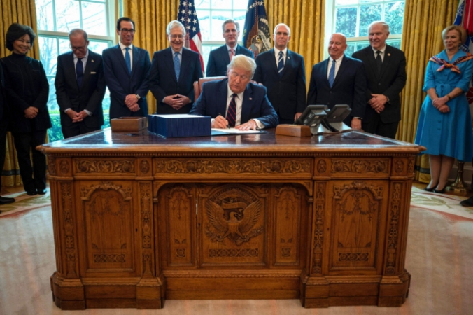 Президент Дональд Трамп подписывает в Овальном кабинете Белого дома закон CARES, пакет для оказания экономической помощи на сумму 2,2 триллиона долларов в условиях вспышки эпидемии 27 марта 2020 года. Jim Watson/AFP via Getty Images | Epoch Times Россия