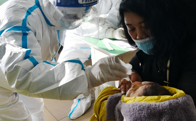 Медицинский работник берет образец мазка у младенца lля теста на COVID-19 в Шицзячжуане, провинция Хэбэй, Китай, 7 января 2021 года. STR/CNS/AFP via Getty Images | Epoch Times Россия