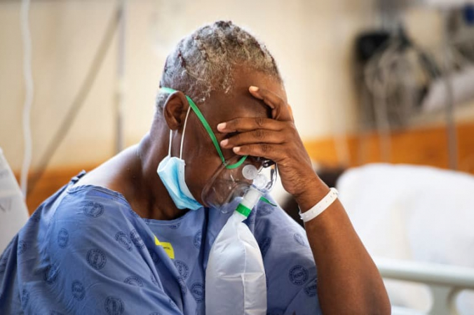 Пациент с COVID-19 в кислородной маске в отделении больницы в 35 км от центра Кейптауна, Южная Африка, 29 декабря 2020 года. RODGER BOSCH/AFP/Getty Images | Epoch Times Россия