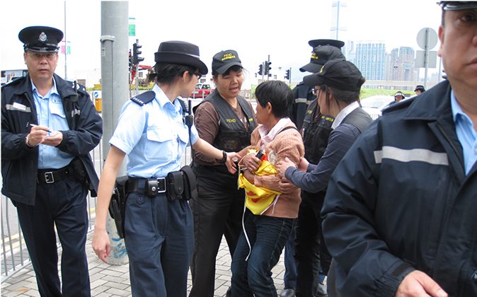 Офицеры полиции  пытаются забрать плакат Фалуньгун, который держала последовательницая г-жа Пун (в центре) 2 мая 2013 г. (Epoch Times) | Epoch Times Россия
