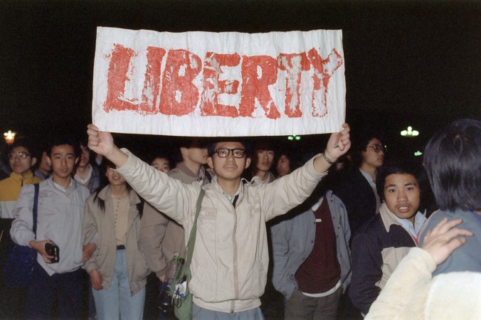 Студент держит плакат с одним из лозунгов, которые скандировали 200 000 человек на площади Тяньаньмэнь 22 апреля 1989 года, через неделю после похорон китайского лидера-реформатора Ху Яобана. Шесть недель спустя танки и солдаты разогнали студенческую демонстрацию. Фото: Catherine Henriette/AFP/Getty Images | Epoch Times Россия