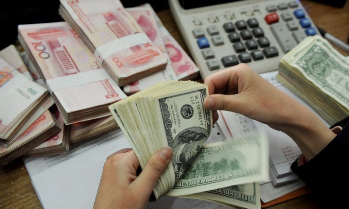 Кассир банка считает пачки долларов США и китайских банкнот 100 юаней в банке в Хэфэе, провинция Аньхой, Китай, 16 января 2011 г. (STR / AFP / Getty Images) | Epoch Times Россия