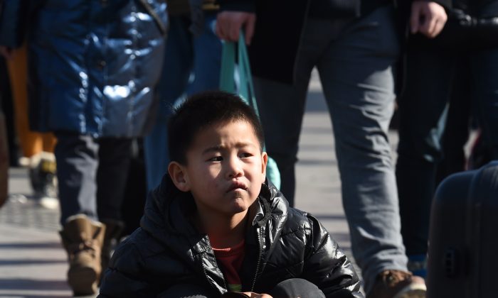Мальчик с родителями ждет у железнодорожного вокзала Пекина 17 февраля 2015 года. Сотни миллионов китайцев возвращаются в свои родные города, чтобы отпраздновать лунный Новый год, который начинается 19 февраля, с семьями, которые являются крупнейшей ежегодной миграцией в мире. . (Грег Бейкер / AFP / Getty Images) | Epoch Times Россия