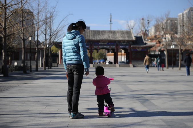 Женщина и ребёнок гуляют в парке в Пекине 26 ноября 2013 года. Китайские власти проводят «политику одного ребёнка» с 1979 года. Фото: Wang Zhao/AFP/Getty Images | Epoch Times Россия